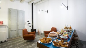 Un comedor con una larga mesa dispuesta para el desayuno, con pasteles, pan y bebidas.