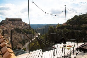 Una terraza con sillas y una mesa, con vistas a un pueblo histórico y una masa de agua.
