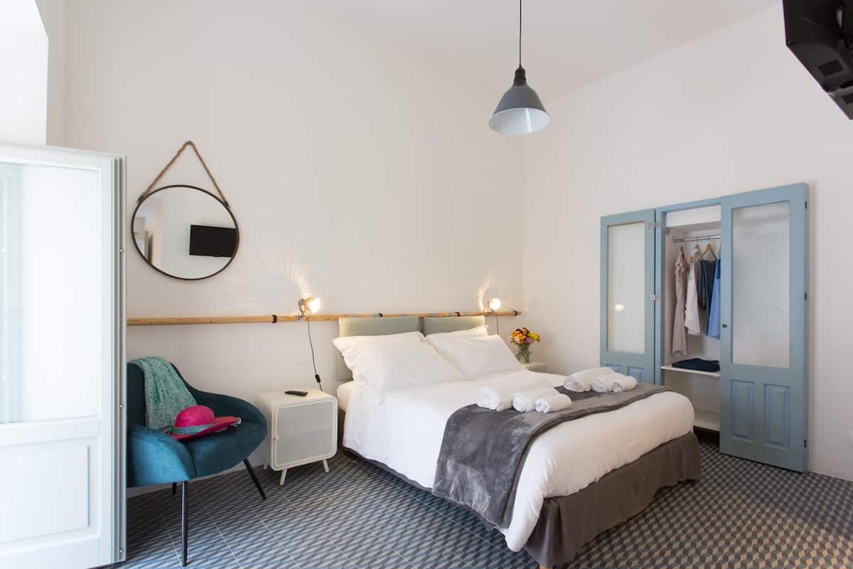 A bedroom with a bed, bedside table, chair, and wardrobe.