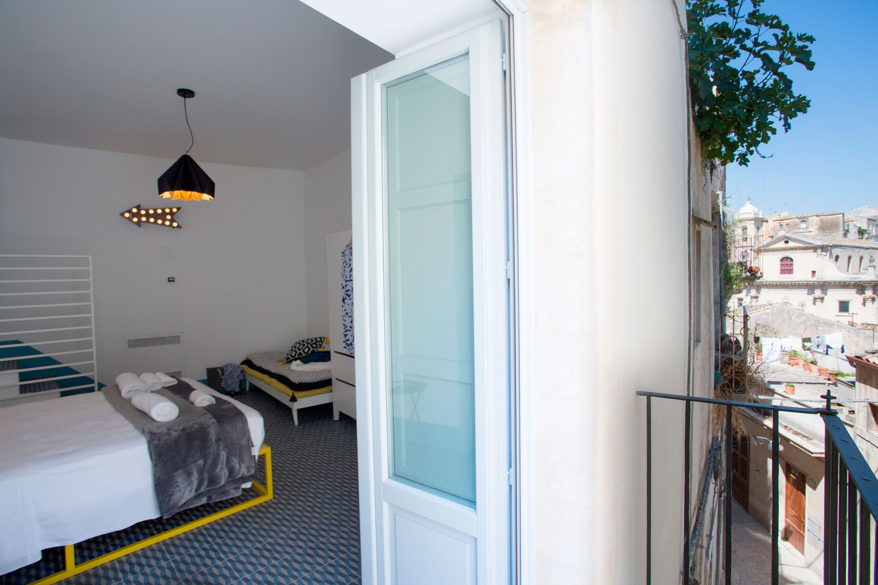 Un dormitorio con cama, mesita de noche y lámpara colgante.