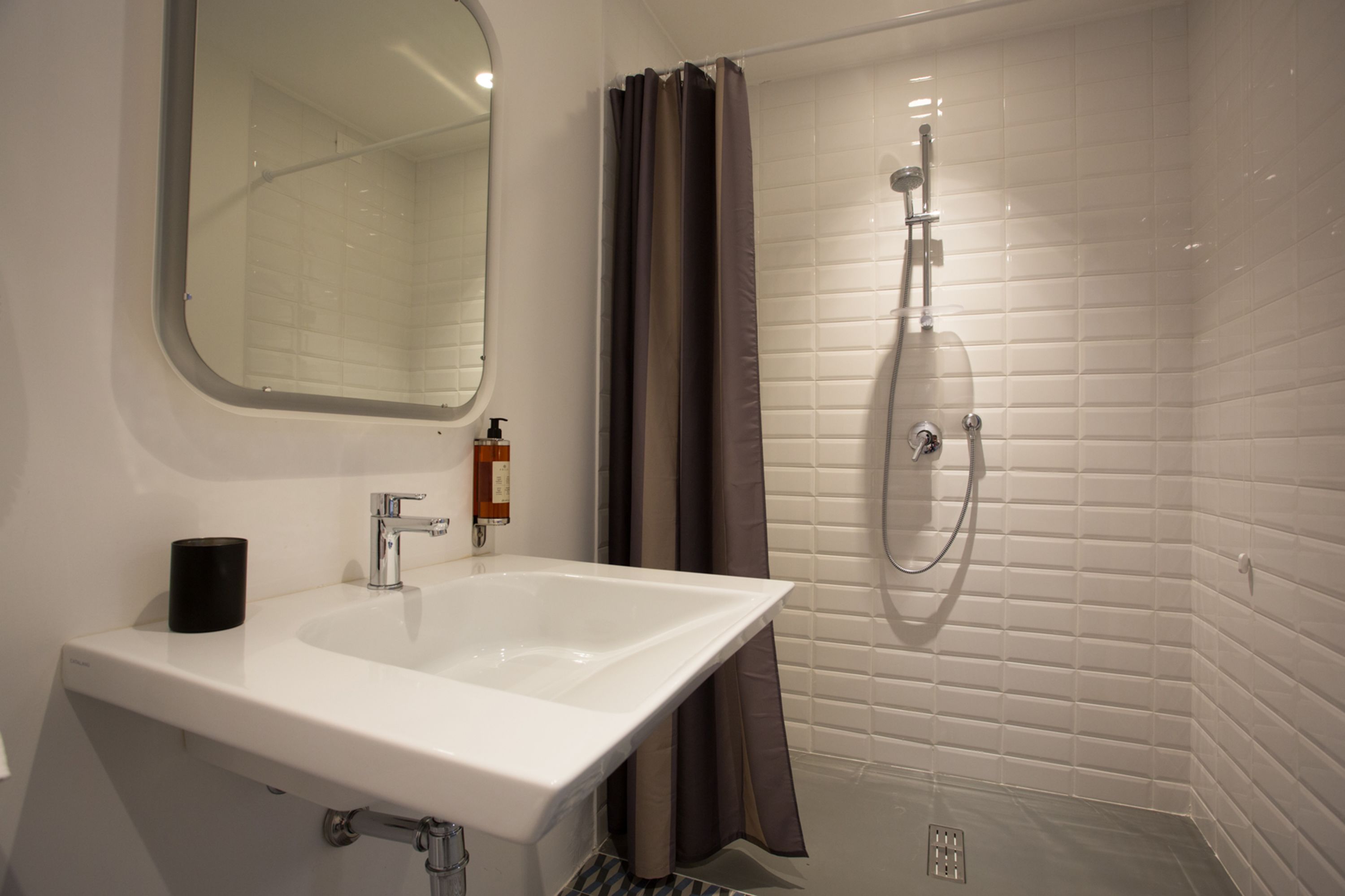 A bathroom with a white sink, a mirror, a shower with a glass door, and a toilet.