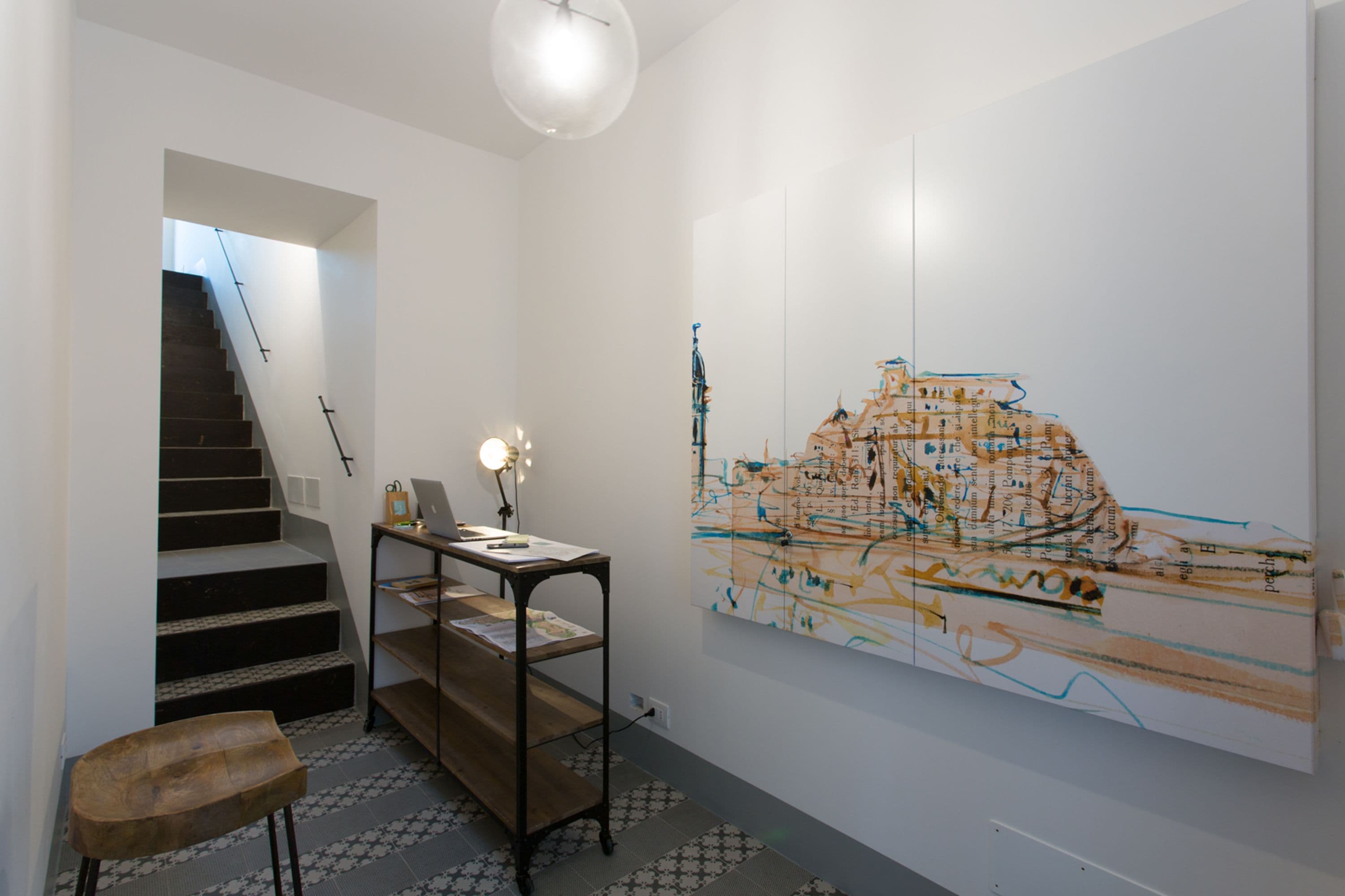 A modern interior with a staircase, a wooden bench, and a large abstract painting on the wall.