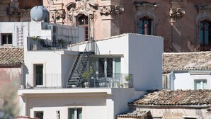 Un edificio de varios pisos con balcones, una escalera de incendios y una antena parabólica.