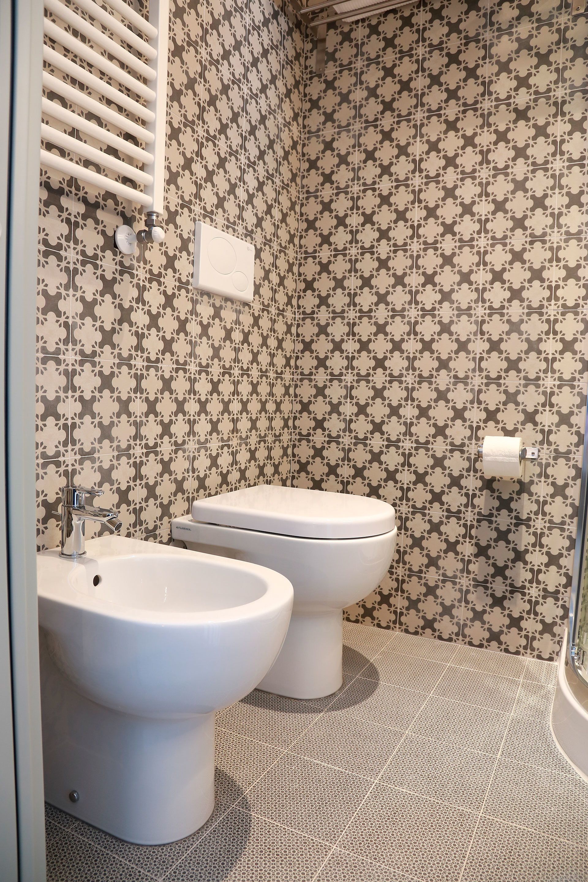 Une salle de bain avec deux toilettes, un bidet et un porte-serviettes.