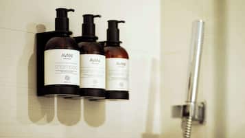 Ein Badezimmer mit drei AVANI Flaschen: Shampoo, Conditioner und Duschgel.
