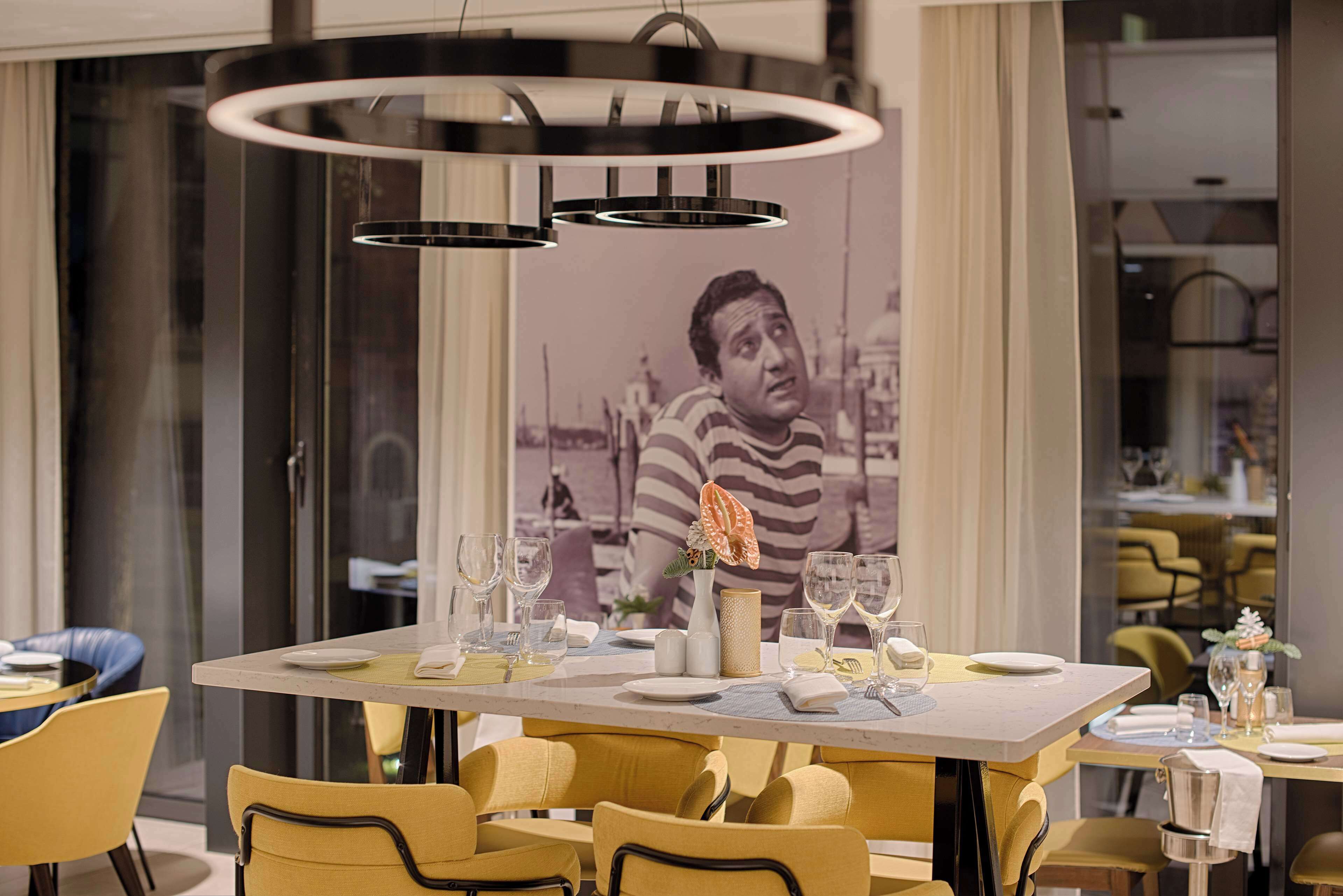 Un comedor con una mesa preparada para dos, sillas y una lámpara colgante moderna.