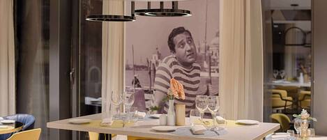 A dining area with a table set for two, chairs, and a modern pendant light fixture.