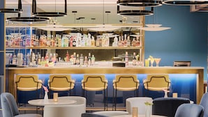 A bar area with multiple seating options, a variety of bottles on shelves, and modern lighting fixtures. - Avani Rio Novo Venice Hotel (Venice)