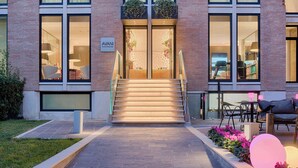 A building with a brick facade, large windows, and a staircase leading to the entrance. - Avani Rio Novo Venice Hotel (Venice)