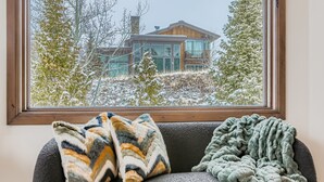 A window with a view of a modern house and a couch with two blankets. - Lucky Star At Belle Arbor 4 Bedroom Home by RedAwning (Park City)