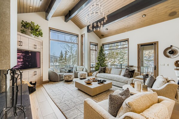 A spacious living room with a large flat-screen TV, a wooden coffee table, and a cozy seating area with sofas and ottomans. - Lucky Star At Belle Arbor 4 Bedroom Home by RedAwning (Park City)