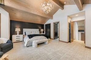 A bedroom with a large bed, bedside tables, a chandelier, and a wooden ceiling. - Lucky Star At Belle Arbor 4 Bedroom Home by RedAwning (Park City)