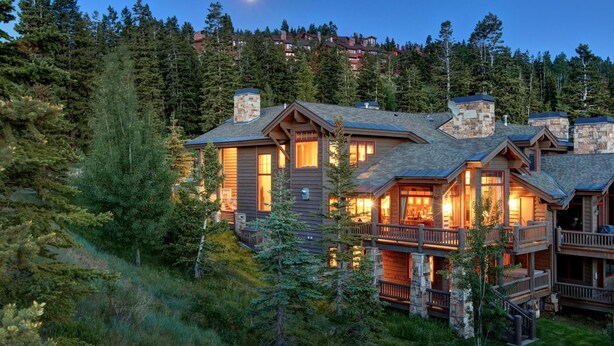 A lodge with multiple wooden structures, stone chimneys, and a balcony overlooking a forested area. - Lucky Star At Belle Arbor 4 Bedroom Home by RedAwning (Park City)