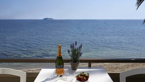 A table with a bottle of champagne, a bowl of strawberries, and a potted plant on a balcony overlooking the sea. - Enkala Apartamentos (Ibiza Town)