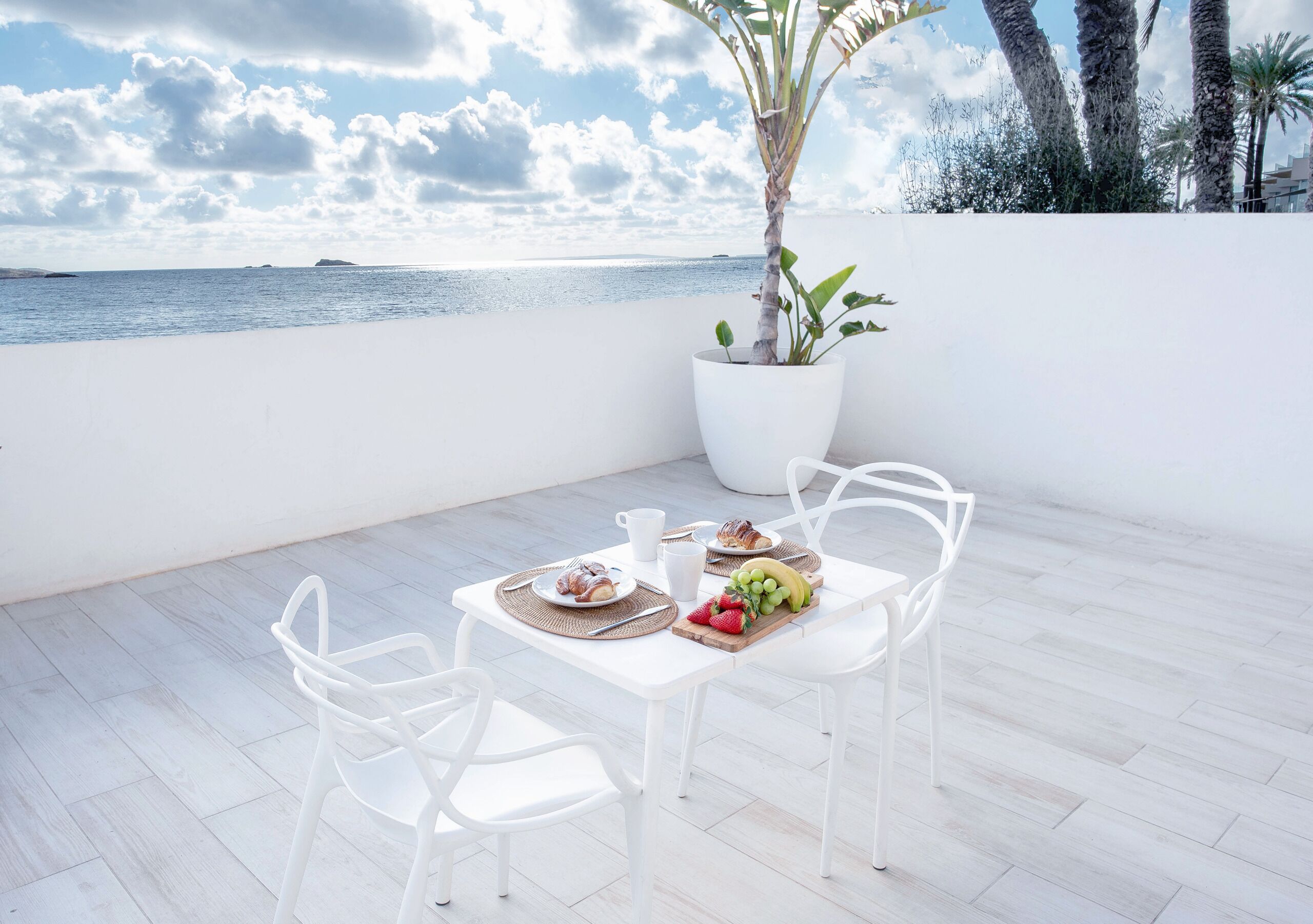 Een eetruimte met een tafel voor twee personen, een potplant en uitzicht op zee.