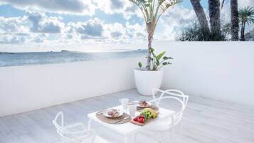 Un comedor con una mesa dispuesta para dos, una planta en maceta y vista al mar.