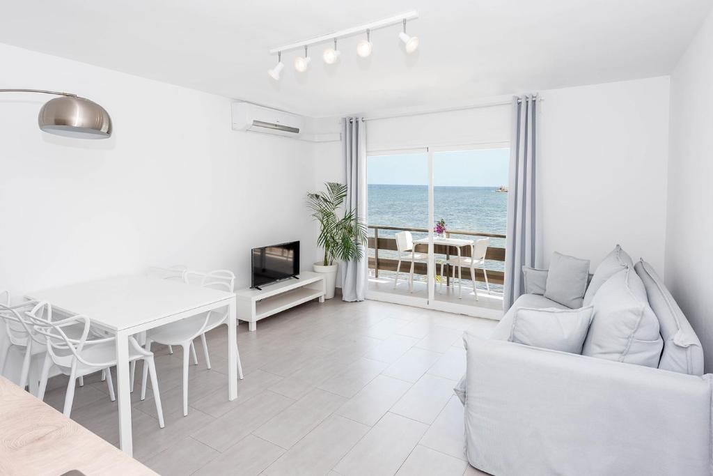 Una sala moderna con comedor, televisor y vista al mar.