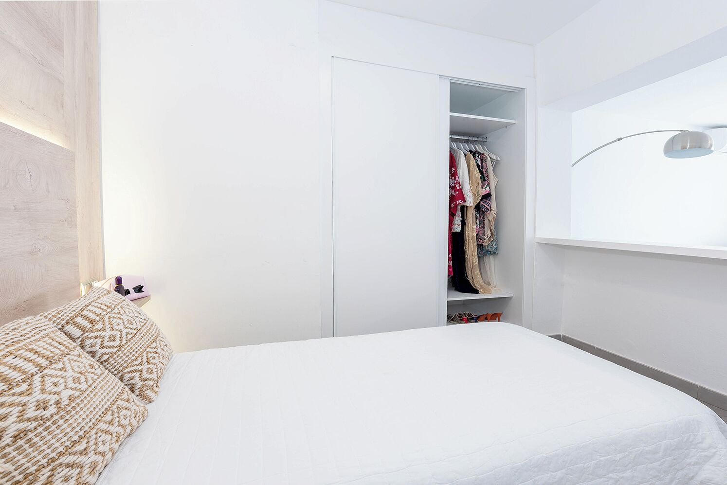 Un dormitorio con cama, armario y mesita de noche con lámpara.