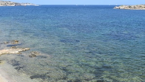 Uma praia costeira com água cristalina e afloramentos rochosos.
