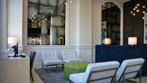 Un vestíbulo moderno con recepción, zona de estar y ventanas amplias.