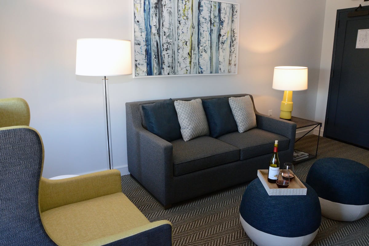 A modern living room with a sofa, two armchairs, a coffee table, and two lamps.