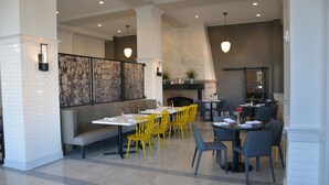 Un restaurante con diversas opciones de asientos, incluidas mesas y un banco, con una chimenea al fondo.