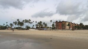 Una playa con palmeras y un edificio de varios pisos con balcones.