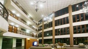 Un vest íbulo amplio con techo alto, varios pisos y una zona de estar central con televisor.