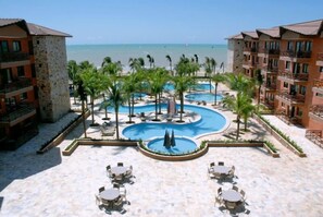 Ein Resort mit mehreren Schwimmbecken, Palmen und Blick auf den Strand.