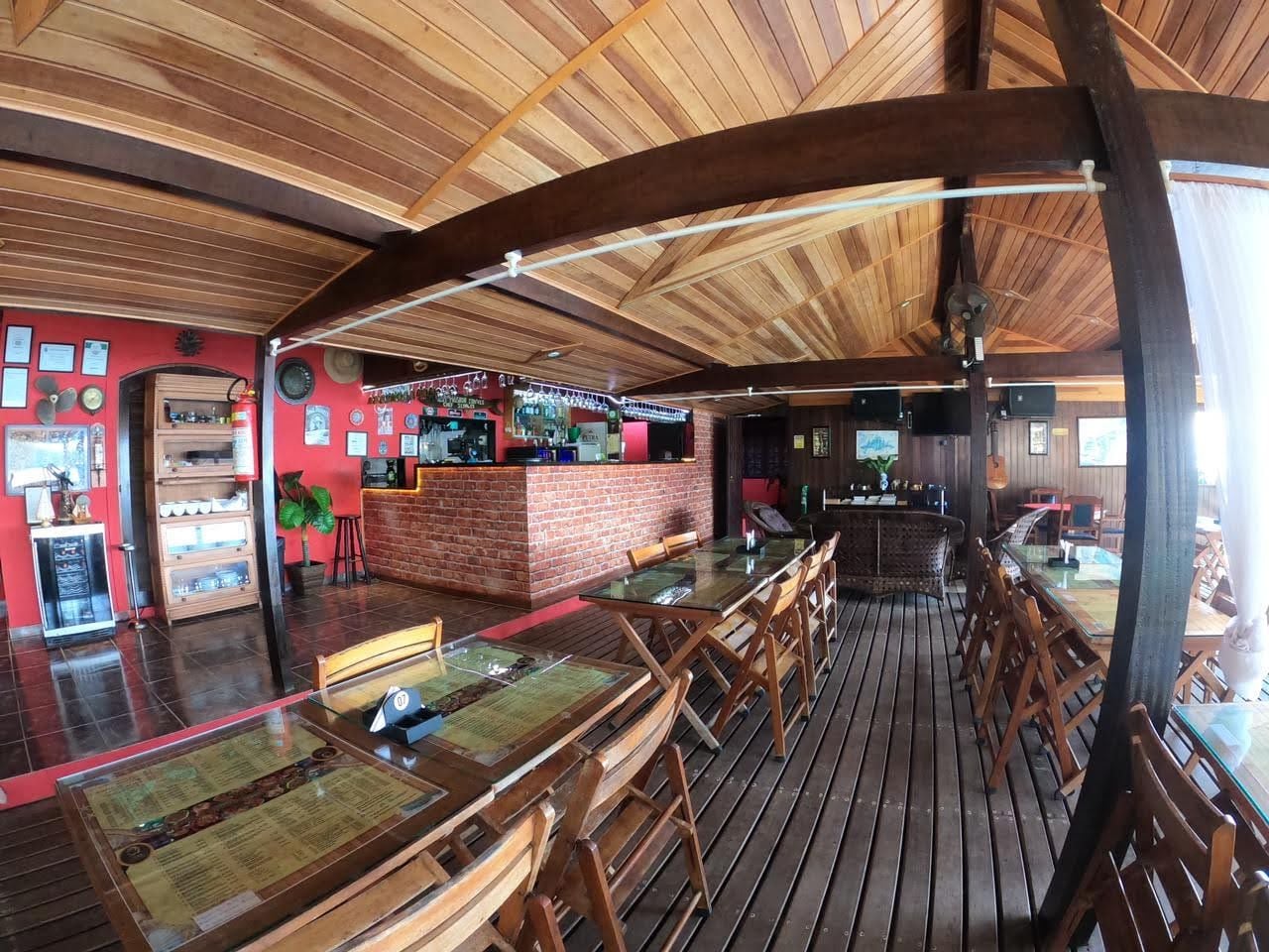 Un restaurante con interior de madera, una zona de bar y un espacio de estar.