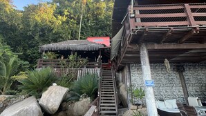 A wooden staircase leading to a building with a thatched roof and a flag. - Pousada Convés Ilha Grande (Angra dos Reis)