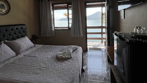 A bedroom with a large bed, a TV, and a view of the outdoors. - Pousada Convés Ilha Grande (Angra dos Reis)