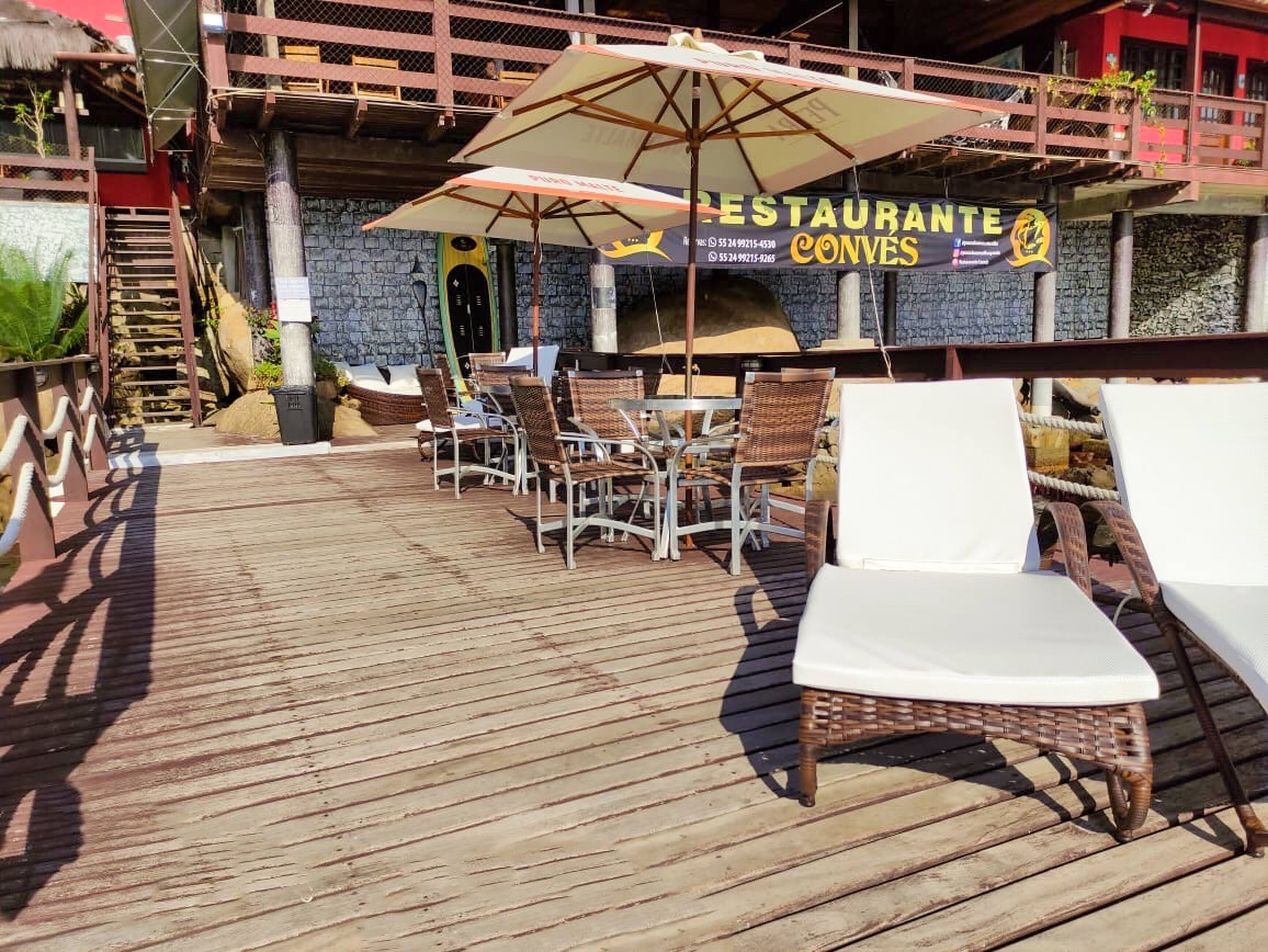 An outdoor patio area with wicker chairs and tables, a wooden deck, and a restaurant sign.