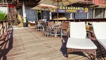 An outdoor patio area with wicker chairs and tables, a wooden deck, and a restaurant sign.