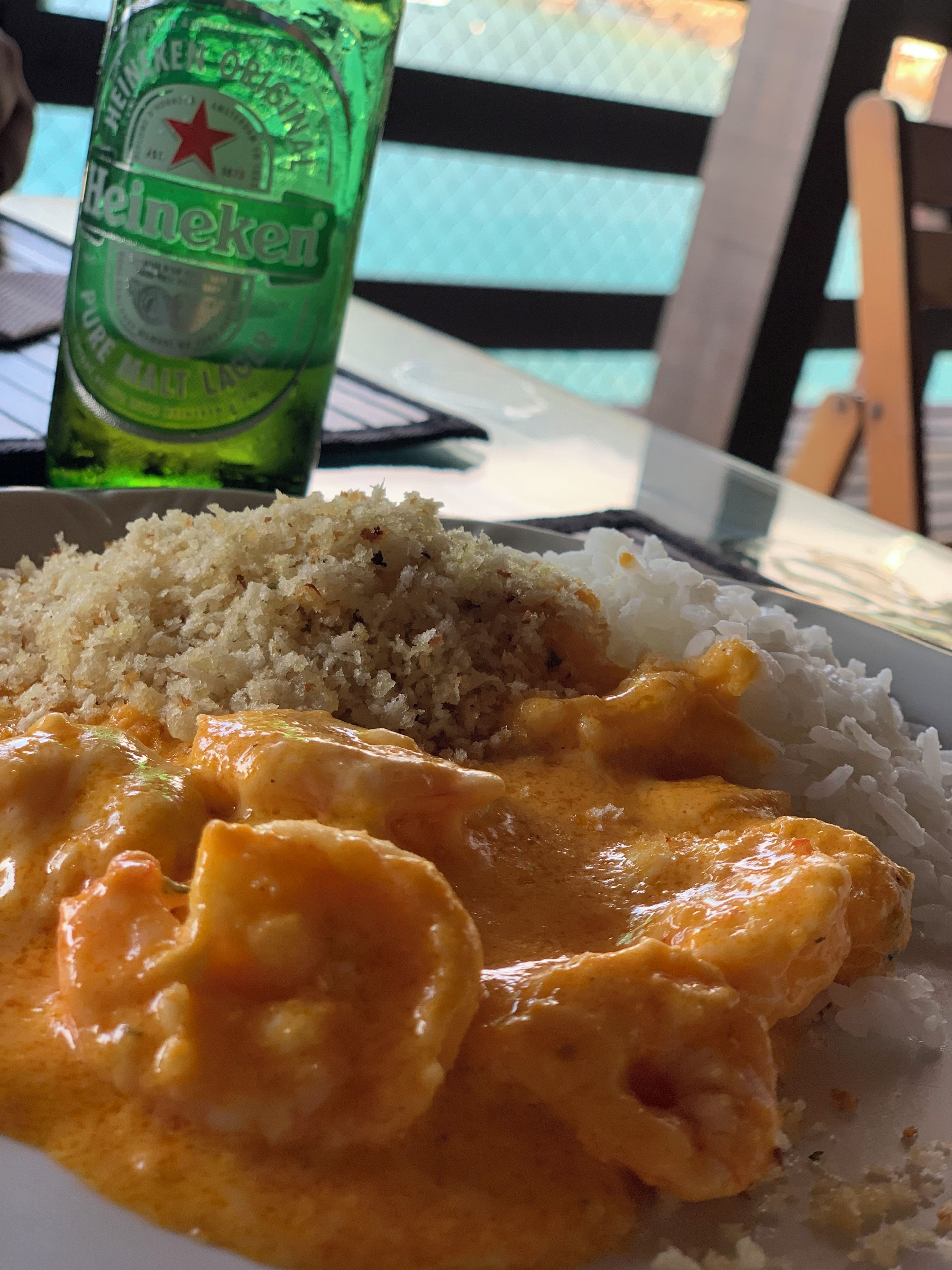 A plate of food with rice and curry, a bottle of beer, and a table setting.
