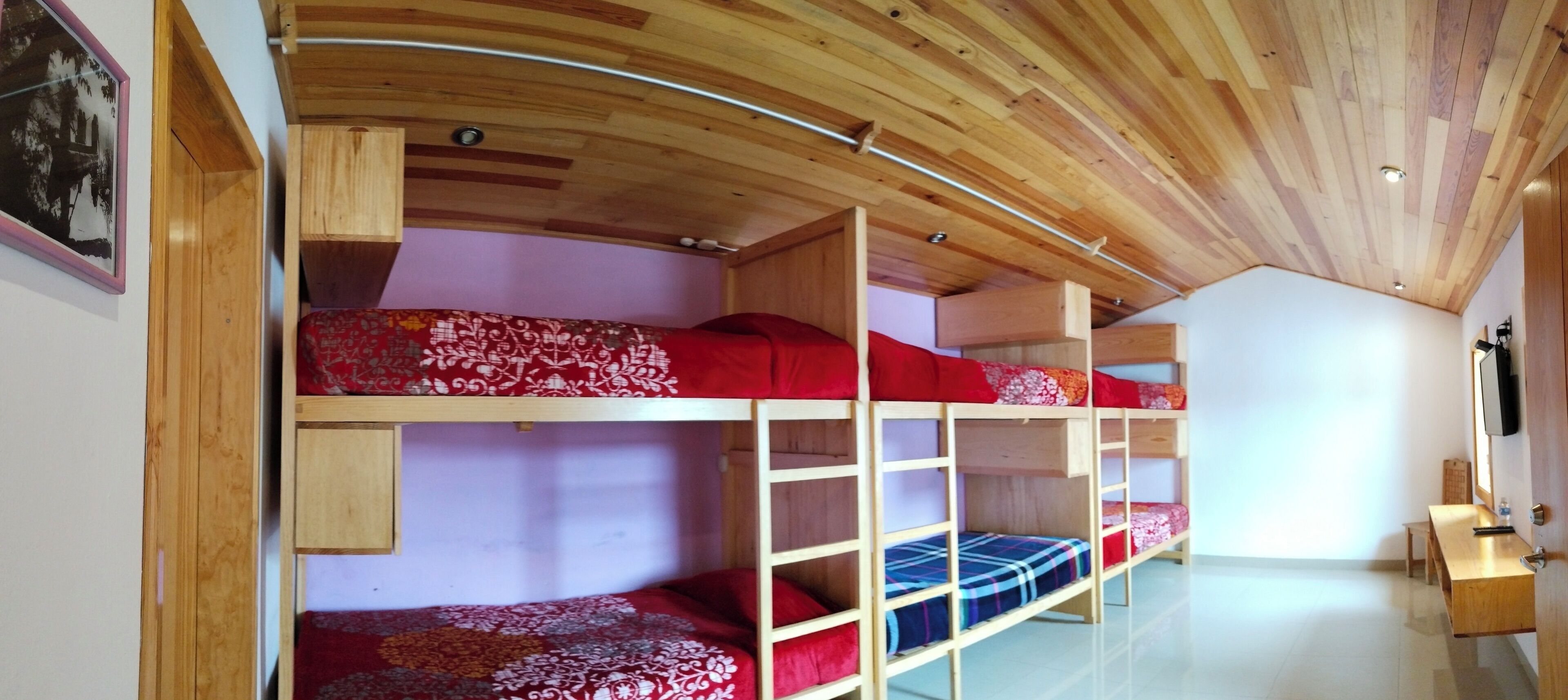 Dormitorio con literas, techos de madera y piso blanco.