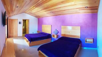 Un dormitorio con dos camas de madera, paredes moradas y techo de madera.
