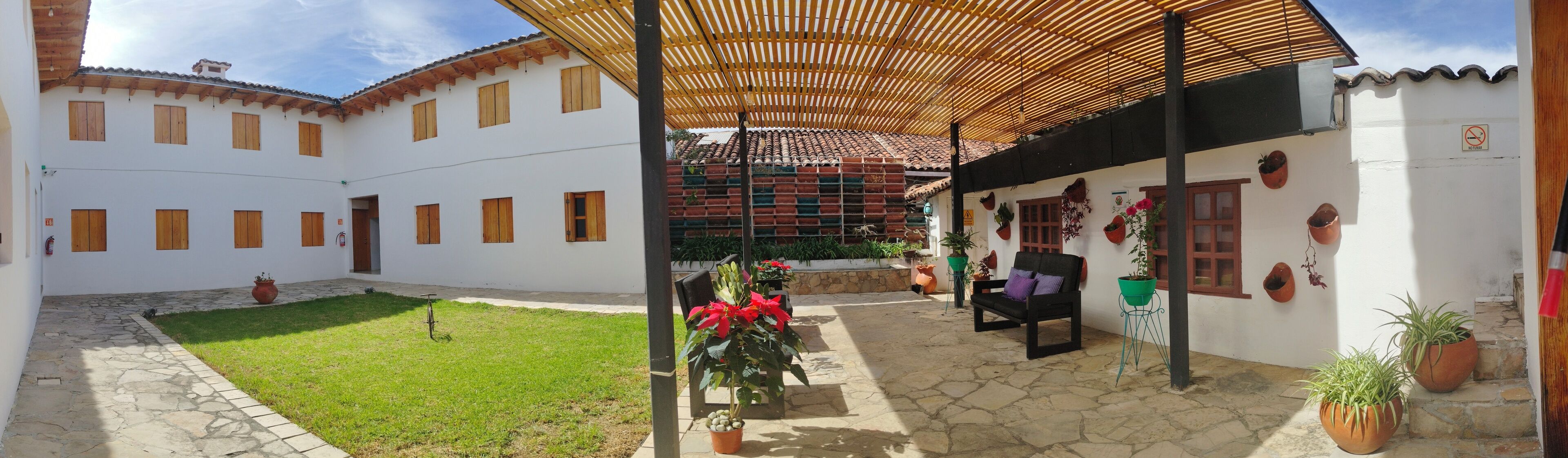 Un patio con una zona de estar techada, un extintor y plantas en macetas.