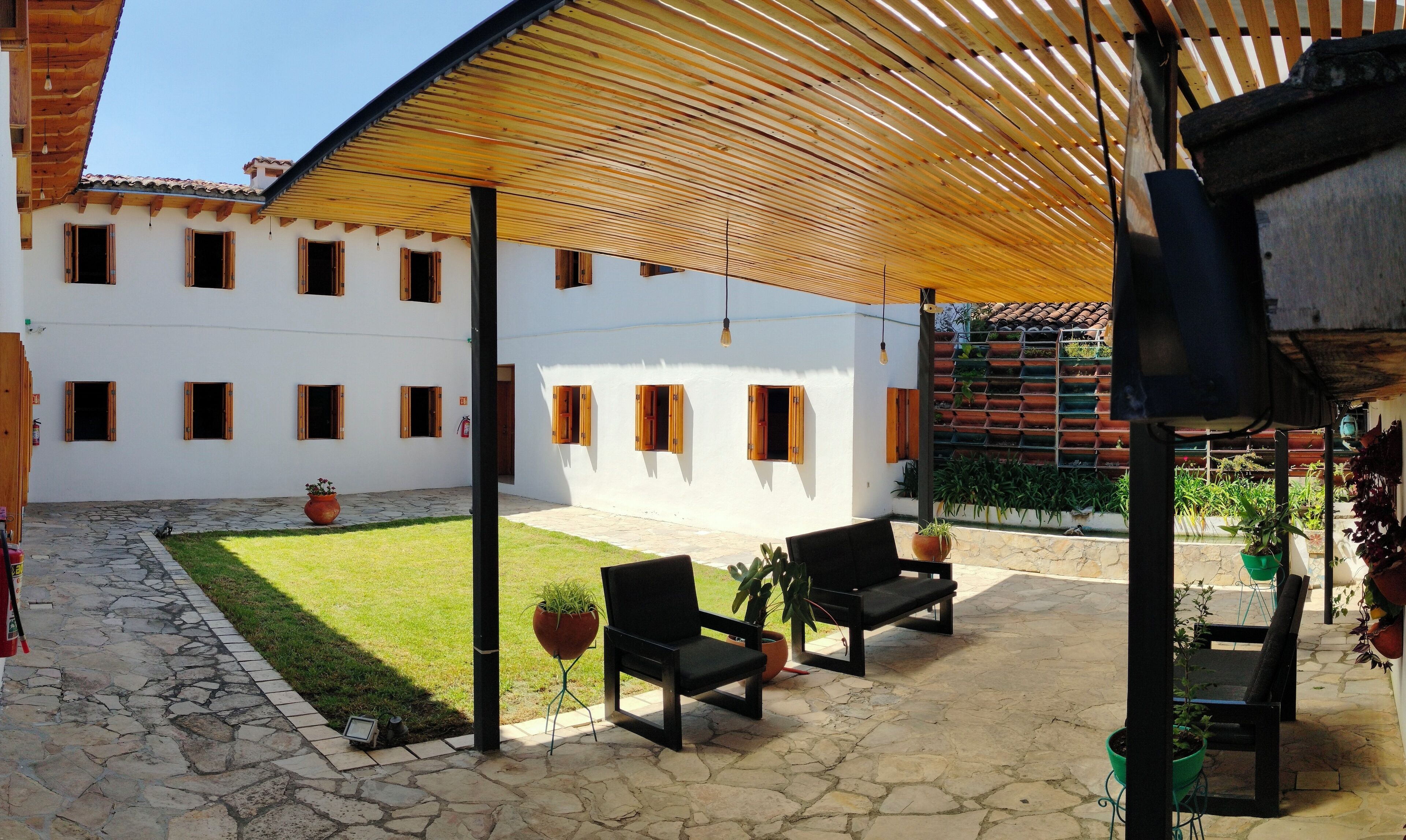 A courtyard with a covered seating area, stone flooring, and potted plants.