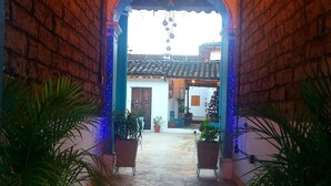A stone-paved courtyard with brick walls, potted plants, and hanging light bulbs. - Hotel Yú (San Cristóbal de las Casas)