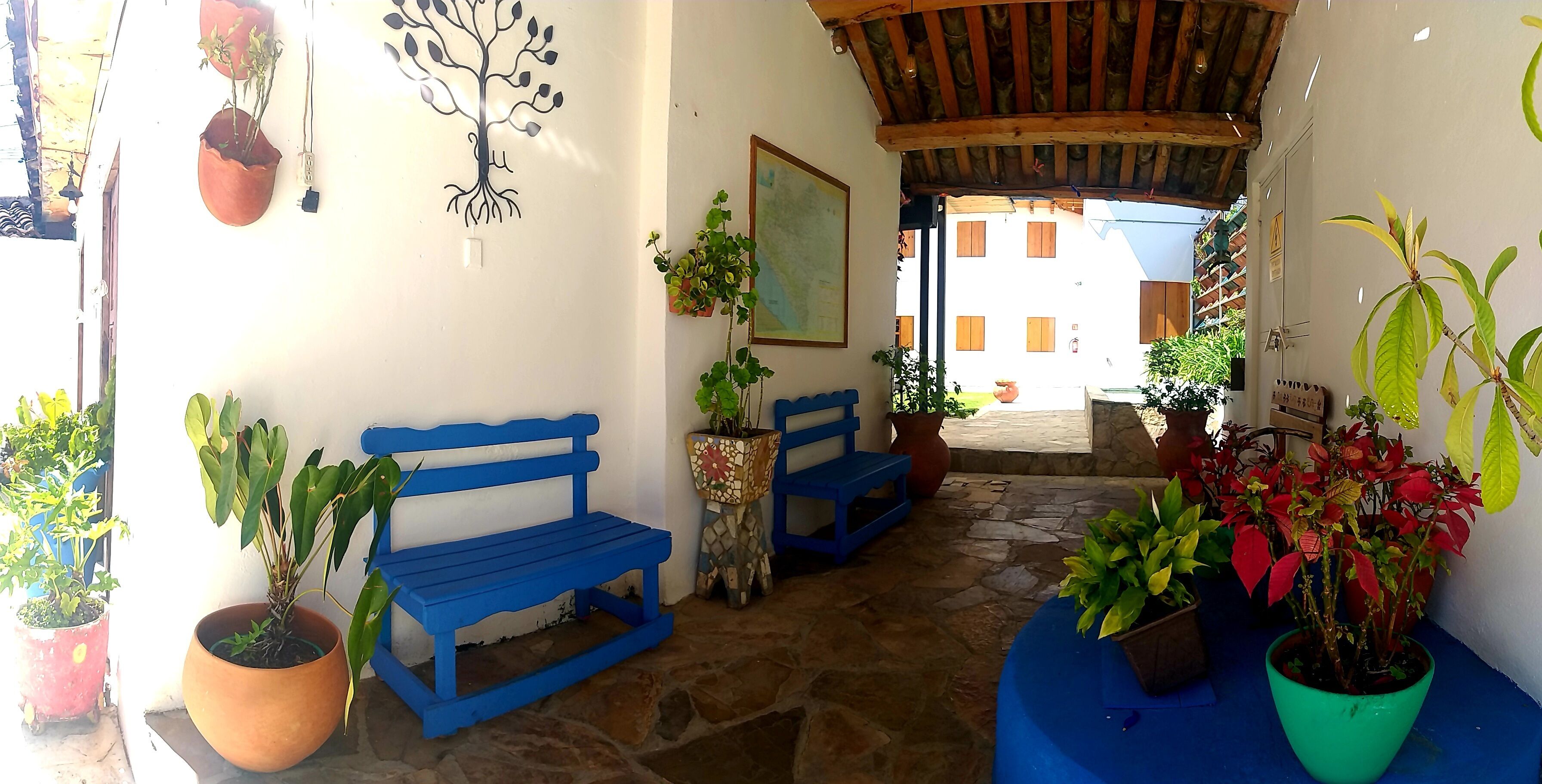 A stone-floored entrance with a blue bench, potted plants, and a wooden ceiling.