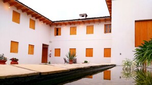 A courtyard with a reflective pool, wooden shutters, and potted plants. - Hotel Yú (San Cristóbal de las Casas)