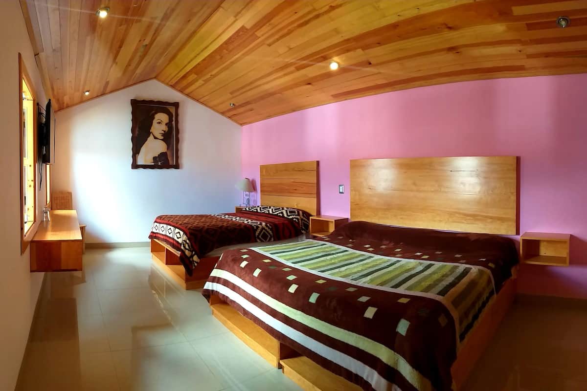 Un dormitorio con dos camas, cabeceros de madera, un cuadro grande en la pared y una ventana con vistas.