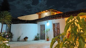 A courtyard with a tiled roof, potted plants, and a building with wooden doors and windows. - Hotel Yú (San Cristóbal de las Casas)