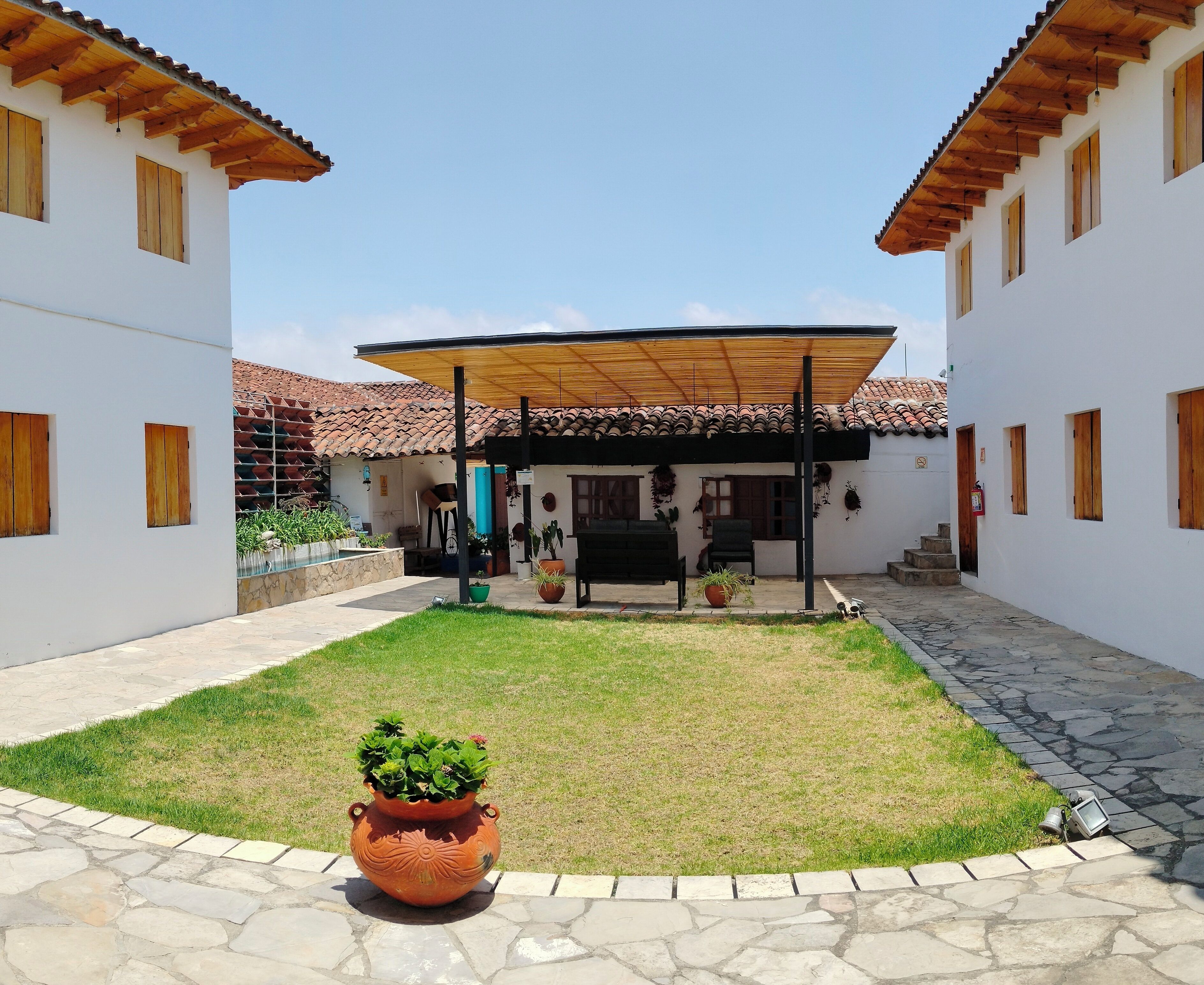 A courtyard with a covered seating area, potted plants, and a stone pathway.