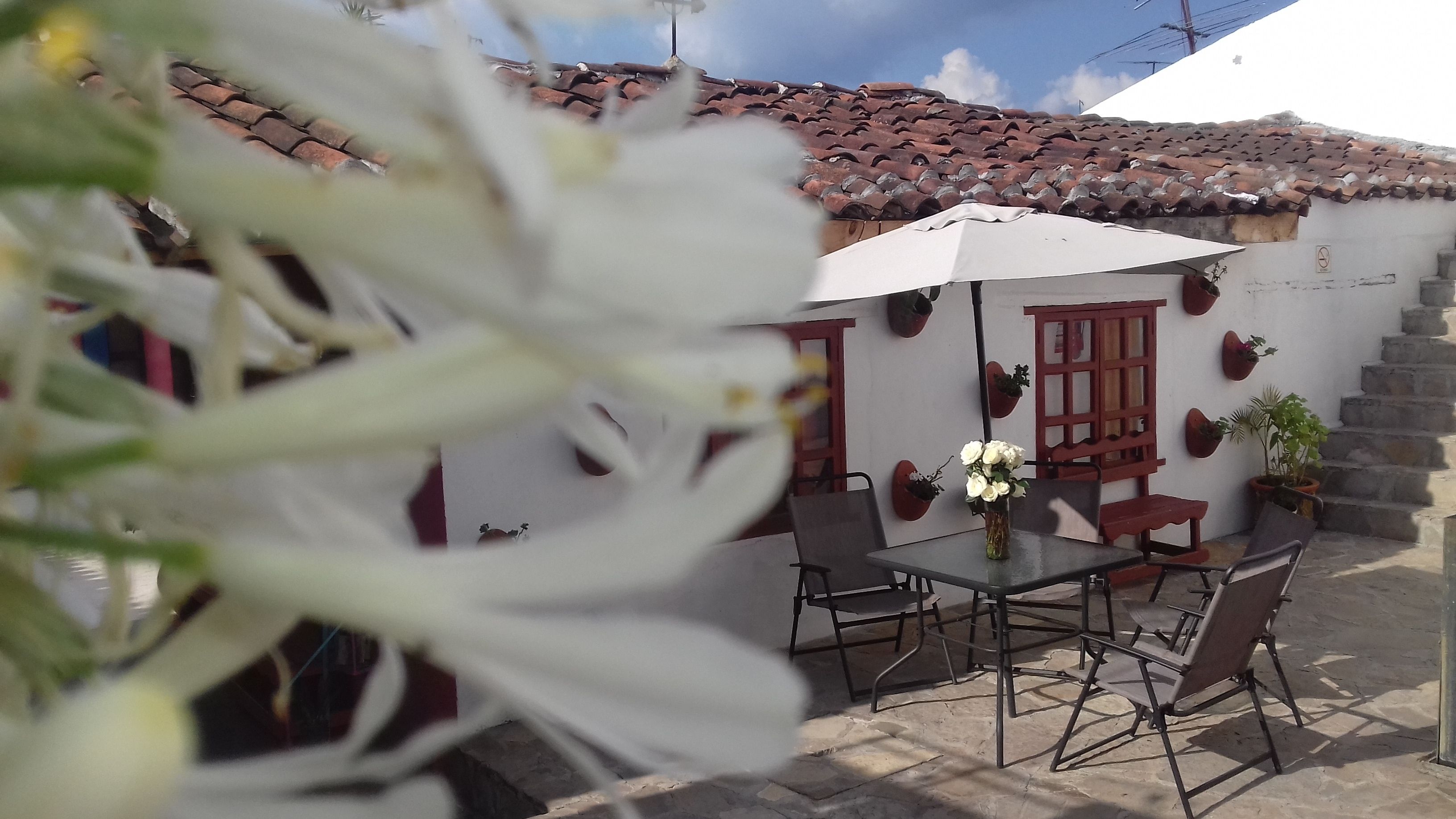 A patio area with a table and chairs, a white umbrella, and a flower vase.