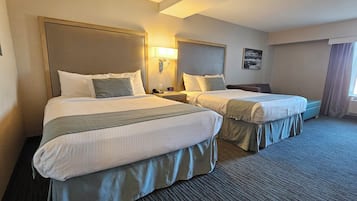 Una habitación de hotel con dos camas, cada una con cabecera, mesitas de noche y lámparas.