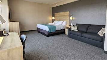A hotel room with a bed, a desk, a sofa, and a TV.