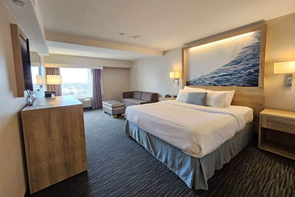 Ein Hotelzimmer mit einem großen Bett, einem Schreibtisch, einem Sessel und einem Nachttisch.