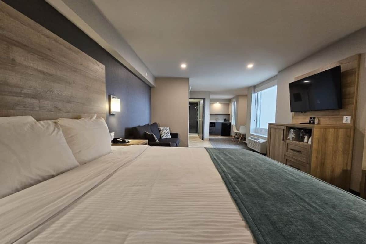 Ein Hotelzimmer mit einem großen Bett, einem Schreibtisch, einem Fernseher und Blick auf den Flur.